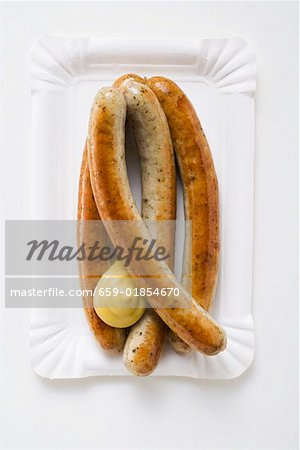 Four sausages with mustard