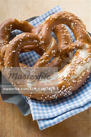 Two salted pretzels on blue and white checked cloth