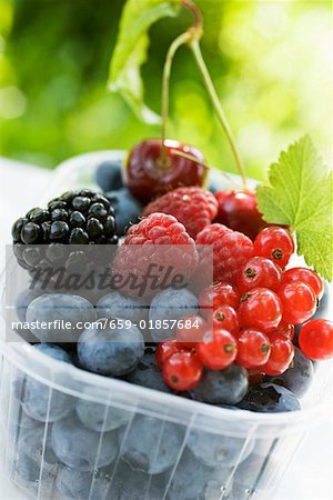 Assorted berries and two cherries in plastic punnet Assorted berries and two cherries in plastic punnet