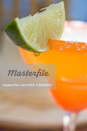 Margarita with wedge of lime in orange glass