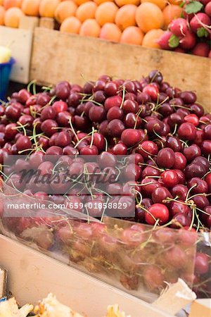 A heap of cherries in a crate at a market
