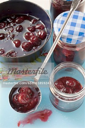 Ladling cherry jam into jars