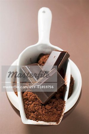 Pieces of chocolate and cocoa powder in scoop and bowl
