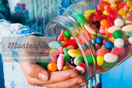 Person tipping sweets out of jar