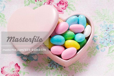 Coloured sugared almonds in pink heart-shaped dish