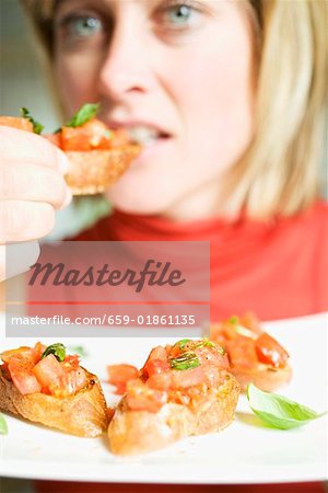 Woman eating bruschetta with fresh basil