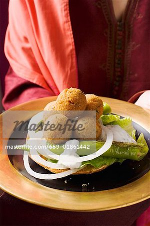 Woman serving falafel (chick-pea balls) with vegetables