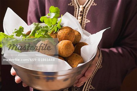 Woman serving falafel (chick-pea balls) in bowl