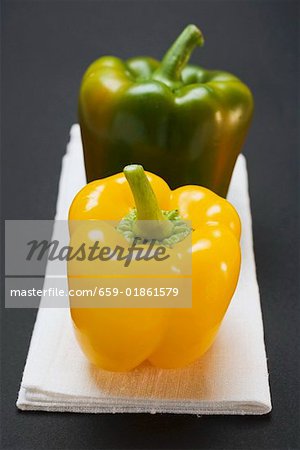 Two peppers (yellow, green) on white linen cloth Two peppers (yellow, green) on white linen cloth