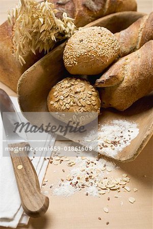 Baguettes & wholemeal rolls in wooden scoop in front of tin loaf