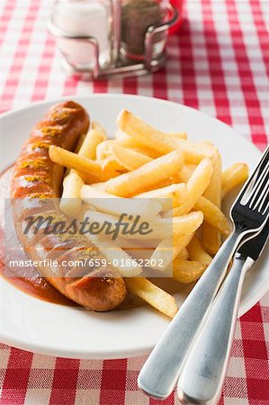 Currywurst (sausage with ketchup & curry powder) & chips in restaurant