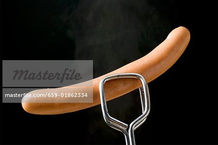 Tongs holding frankfurter