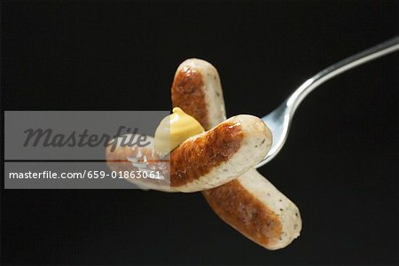 Sausages with mustard on fork