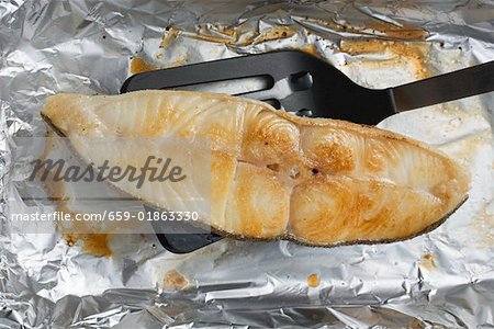 Grilled cod steak on aluminium foil with spatula