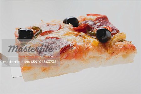 Slice of pepperoni pizza with peppers and olives