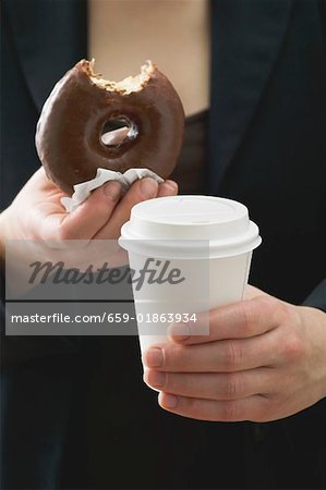 Woman holding doughnut (a bite taken) & plastic coffee cup