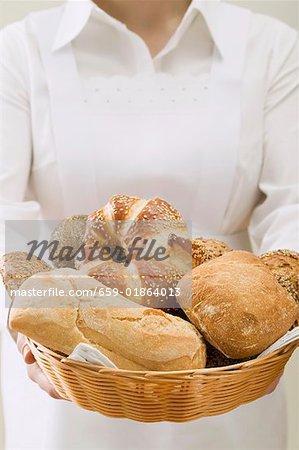 Chambermaid serving assorted bread rolls in bread basket