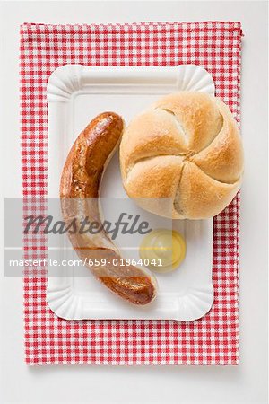 Sausage (bratwurst) with mustard & bread roll on paper plate