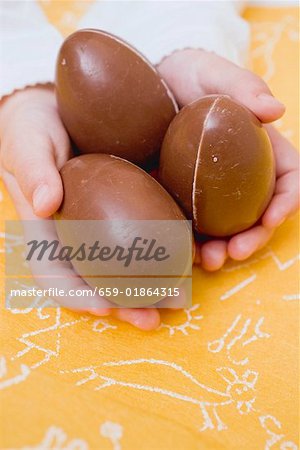 Child's hands holding three chocolate eggs