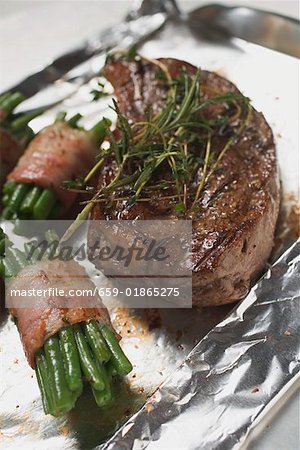 Beef steak with bacon-wrapped beans on aluminium foil