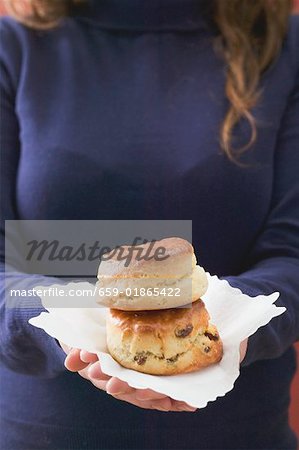 Woman holding two scones on paper napkin