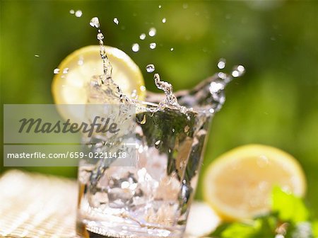 Ice cube falling into glass of water