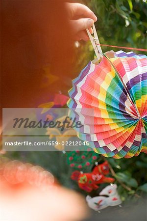 Woman hanging coloured Chinese lantern on washing line in garden
