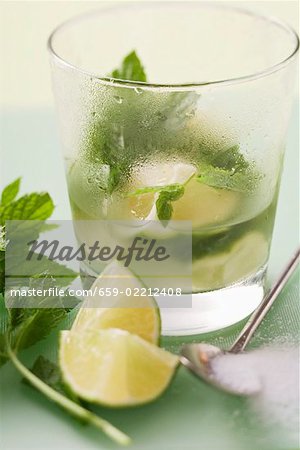 Glass of Mojito with lime & mint, surrounded by ingredients Glass of Mojito with lime & mint, surrounded by ingredients