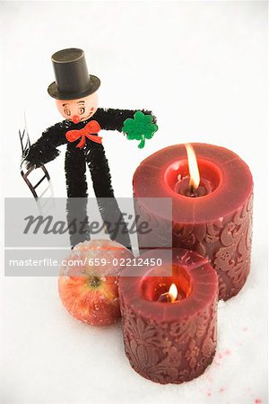 Chimney sweep, apple and red candles in snow