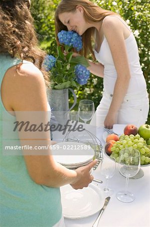 Two women laying the table for a garden party