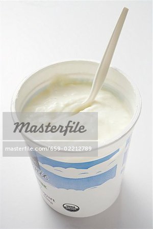 Natural yoghurt in pot with plastic spoon