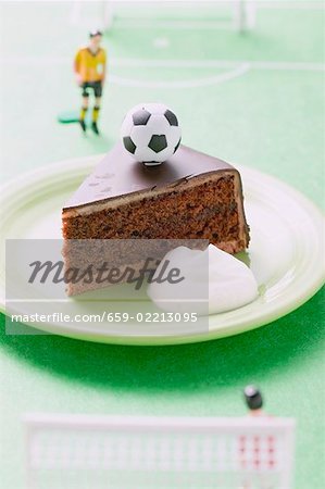 Piece of Sacher torte with cream, football & football figure