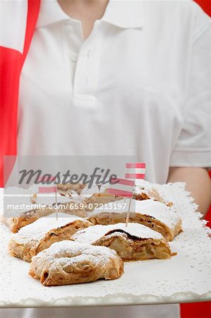 Woman holding several pieces of apple strudel on tray (Austria)