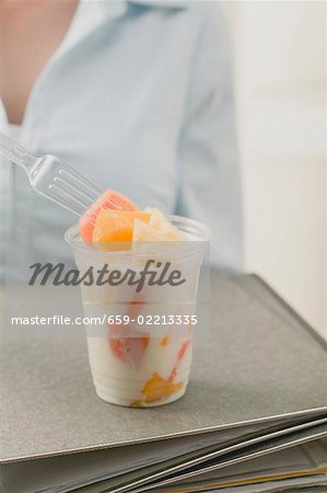 Woman eating fruit yoghurt in office