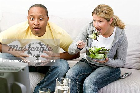 Couple in front of TV with football and salad