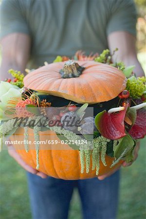 Man holding pumpkin decorated with flowers