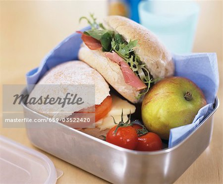 Two sandwiches, apple and tomatoes in a lunch box