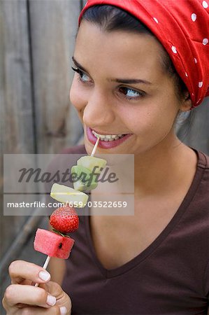 Young woman with fruit skewer