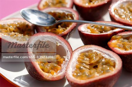 Halved passion fruits with spoon
