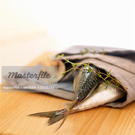 Two mackerel in a fabric napkin with mushroom and thyme