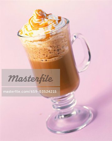 A glass of hot chocolate with whipped cream and caramel sauce