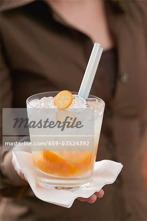 Woman serving drink with kumquats and ice cubes Woman serving drink with kumquats and ice cubes
