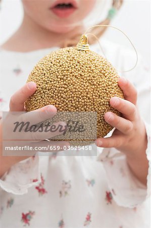 Small girl holding gold Christmas bauble
