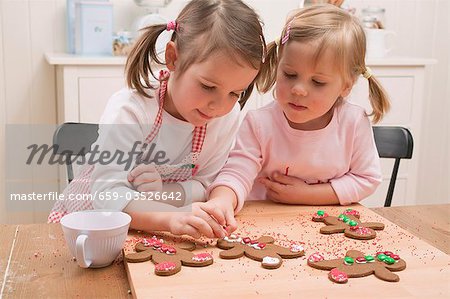 Two small girls decorating gingerbread men