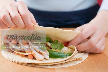 Folding a tortilla over chicken filling