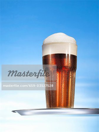 Glass of beer with head on tray