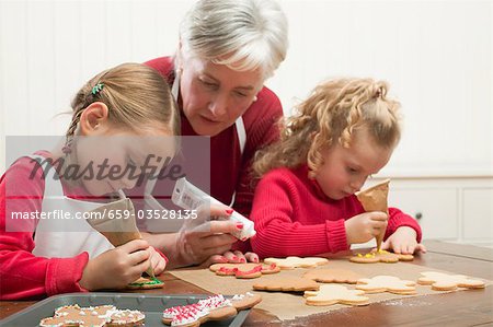 Grandmother & two granddaughters decorating Christmas biscuits