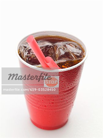 Cola with ice cubes and straw in plastic cup