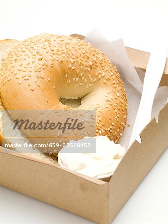 Sesame bagel with crème fraîche in a cardboard box