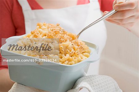 Woman holding baking dish of macaroni cheese